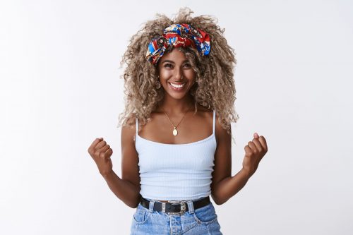 Optimistic, encouraged good-looking african american blond female with afro hairstyle, fist pump move and smiling from victory, winning lottery, celebrating amazing achievement, white background.