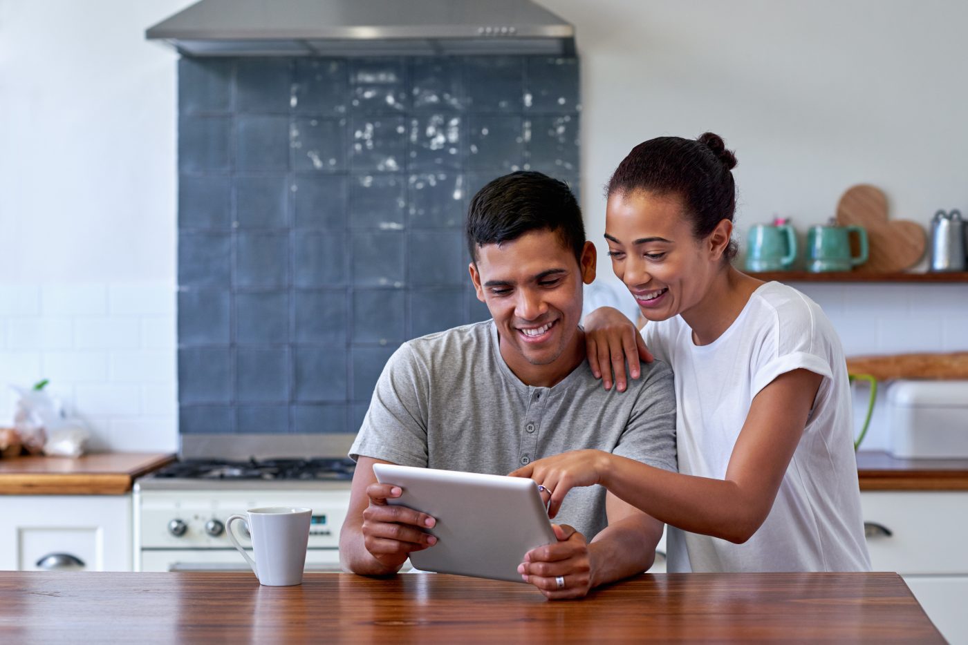 couple bonding and enjoying morning coffee with tablet computer in kitchen at home